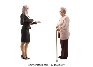 Full Length Profile Shot Of A Businesswoman Talking To An Elderly Woman With Protective Face Masks Isolated On White Background