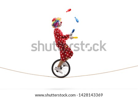 Full length profile shot of a clown juggling with clubs and riding a unicycle on a rope isolated on white background
