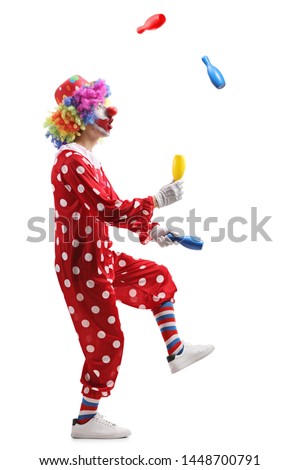 Full length profile shot of a clown juggling with clubs isolated on white background 