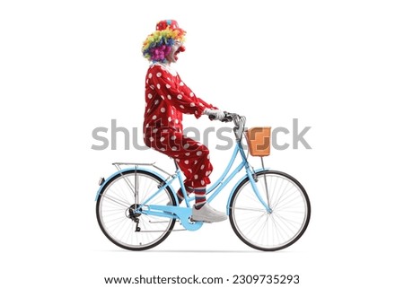 Full length profile shot of a clown riding a bicycle isolated on white background