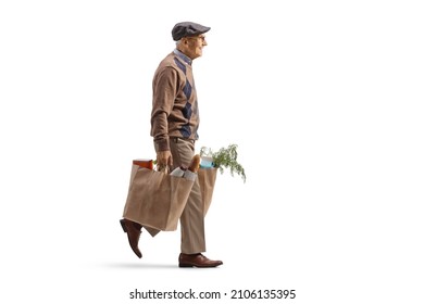 Full Length Profile Shot Of An Elderly Man Carrying Grocery Bags And Walking Isolated On White Background