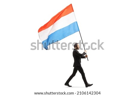 Full length profile shot of an elegant man in a suit walking and carrying a dutch flag isolated on white background