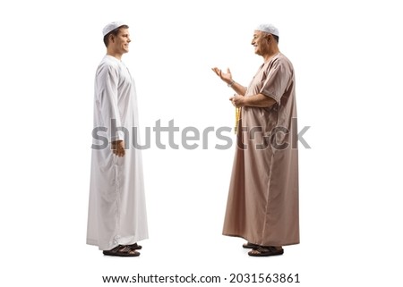 Full length profile shot of a father and son in ethnic clothes having a conversation isolated on white background