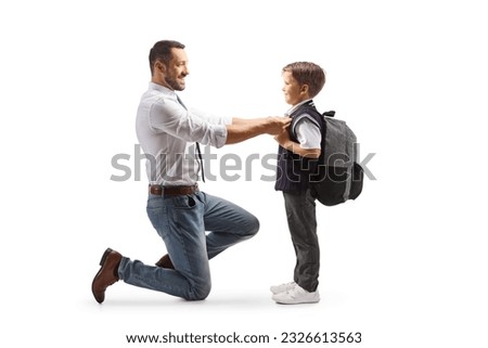 Full length profile shot of a father helping his son getting ready for school isolated on white background