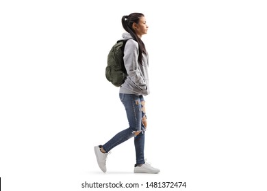 Full length profile shot of a female student wearing a hoodie and ripped jeans walking isolated on white background