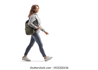 Full length profile shot of a female student in jeans with a backpack walking isolated on white background