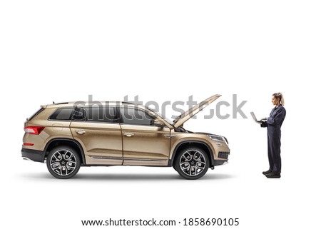 Full length profile shot of a female auto mechanic with a laptop computer checking a SUV isolated on white background