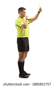 Full length profile shot of a football referee blowing a whistle and holding a yellow card isolated on white background