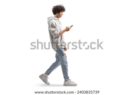 Full length profile shot of a gen z guy wearing a gray hoodie and walking with a smartphone isolated on white background