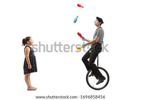 Full length profile shot of a girl watching a mime juggling and riding a unicycle isolated on white background