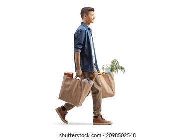 Full length profile shot of a guy carrying grocery bags and walking isolated on white background
