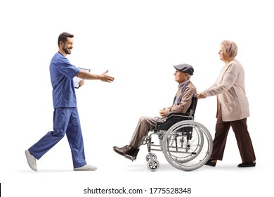 Full Length Profile Shot Of A Male Health Worker Walking And Welcoming Elderly Man In A Wheelchair Isolated On White Background