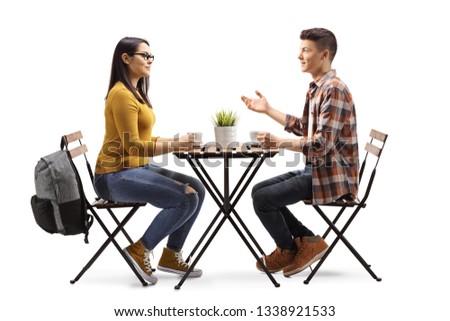Full length profile shot of a male and female student having a coffee and talking in a cafe isolated on white background