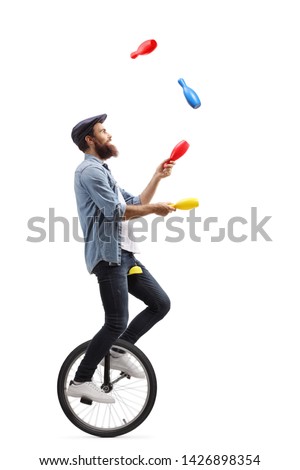 Full length profile shot of a male juggler on a unicycle juggling with clubs isolated on white background