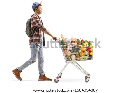 Full length profile shot of a male student with food in a shopping cart isolated on white background
