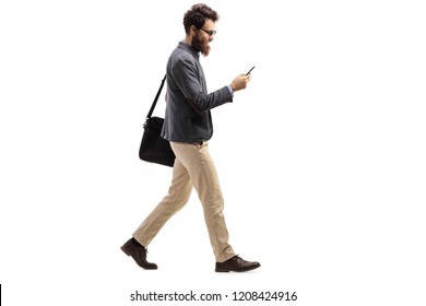 Full length profile shot of a man walking and looking into a mobile phone isolated on white background - Shutterstock ID 1208424916