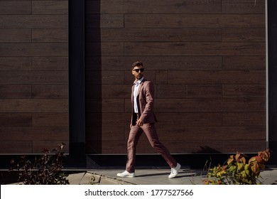 Full Length Profile Shot Of A Man Walking And Looking To The Side Against The Backdrop Of An Office Center In Hot Weather. After Work, The Man Returns Home.