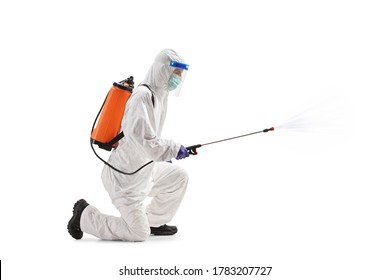 Full Length Profile Shot Of A Man In A Hazmat Suit Kneeling And Using A Sanitizing Spray Isolated On White Background