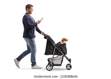 Full Length Profile Shot Of A Man Pushing A Dog Stroller And Typing On A Mobile Phone Isolated On White Background