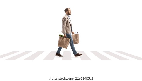 Full length profile shot of a man with grocery bags walking on a pedestrian crossing isolated on white background - Powered by Shutterstock