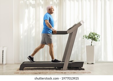 Full Length Profile Shot Of A Mature Man Walking On A Treadmill At Home 