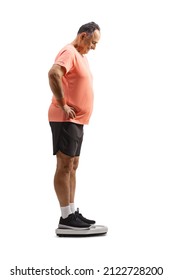 Full Length Profile Shot Of A Mature Man In Sportswear Standing On A Weight Scale Isolated On White Background