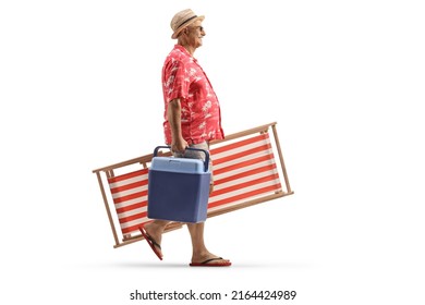 Full Length Profile Shot Of A Mature Man Carrying A Beach Chair And A Portable Mini Fridge Isolated On White Background