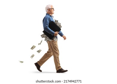 Full length profile shot of a mature man walking with a briefcase full of money isolated on white background - Shutterstock ID 2174942771
