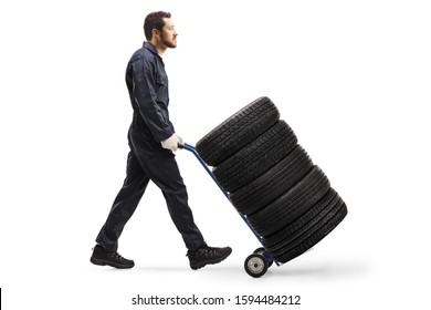 Full Length Profile Shot Of A Mechanic Pushing Car Tires On A Hand Truck Isolated On White Background