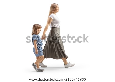Full length profile shot of a mother and daughter walking holding hands isolated on white background