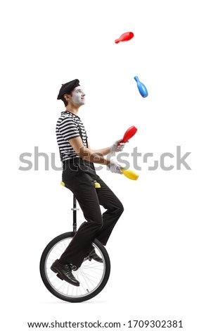 Full length profile shot of a pantomime guy riding a mono-cycle and juggling isolated on white background