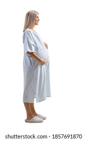 Full Length Profile Shot Of A Pregnant Woman Patient Posing In A Hospital Gown Isolated On White Background