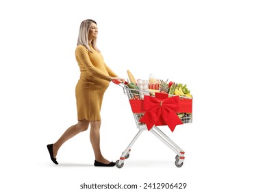 Full length profile shot of a pregnant woman pushing a shopping cart with healthy food tied with a red ribbon isolated on white background - Powered by Shutterstock