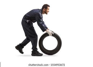 Full length profile shot of a repairman rolling a car tire isolated on white background