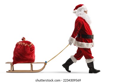 Full length profile shot of santa claus pulling a wooden sled with a red sack full of presents isolated on white background