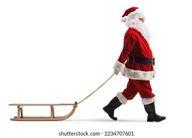 Full length profile shot of santa claus pulling a wooden sleigh isolated on white background