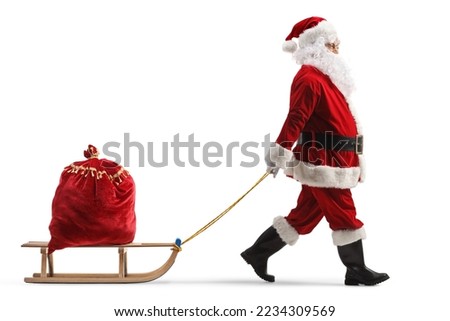Full length profile shot of santa claus pulling a wooden sled with a red sack full of presents isolated on white background