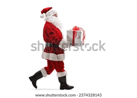 Full length profile shot of santa claus walking and carrying a present box isolated on white background