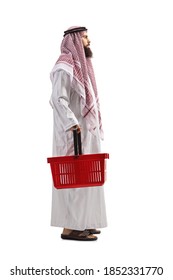 Full Length Profile Shot Of A Saudi Arab Man In A Thobe Standing With A Shopping Basket Isolated On White Background