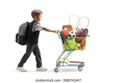 Full length profile shot of a schoolboy pushing a mini shopping cart with sport equipment isolated on white background  