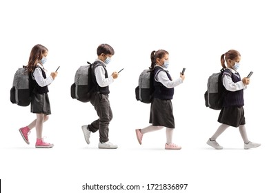 Full length profile shot of schoolchildren with protective face masks walking in line and holding mobile phones isolated on white background - Powered by Shutterstock