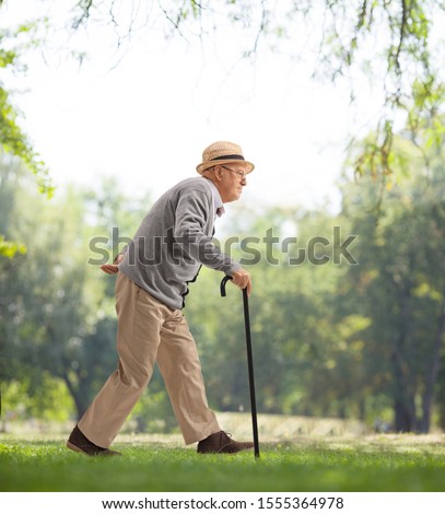 Full length profile shot of a senior man walking with a cane in a park