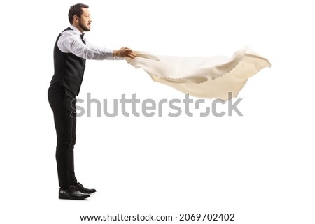 Full length profile shot of a server holding a tablecloth isolated on white background