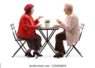 Full Length Profile Shot Of Two Senior Women Drinking Coffee And Talking Isolated On White Background