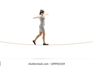 Full length profile shot of a woman walking on a rope and wearing blindfold isolated on white background