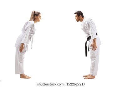 Full length profile shot of a woman with white belt in karate and a man with black belt bowing at each other isolated on white background - Powered by Shutterstock