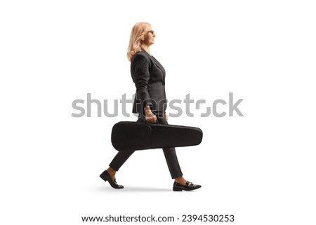 Full length profile shot of a woman walking and carrying a violin in a case isolated on white background