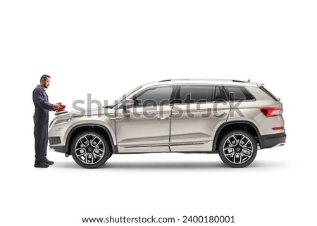 Full length profile shot of a worker polishing a car with a buffer isolated on white background
