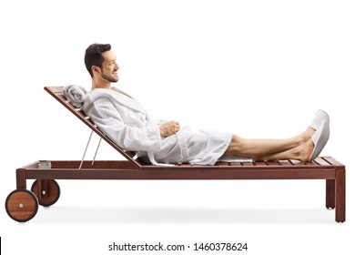 Full Length Profile Shot Of A Young Man In A Bathrobe Relaxing On A Lounge Chair Isolated On White Background