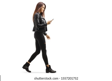 Full length profile shot of a young female walking and looking at her mobile phone isolated on white background